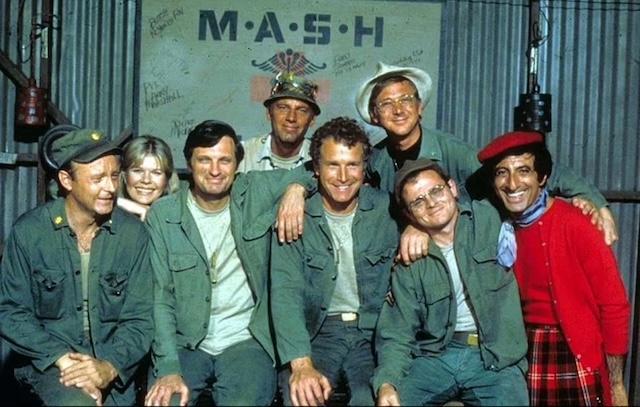 The Cast of M*A*S*H: The iconic ensemble cast of the beloved TV series M*A*S*H posing together in the familiar setting of the 4077th M*A*S*H unit