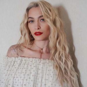 Paris stuns in a white off-shoulder top and bold red lipstick.